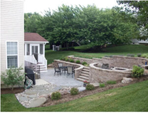 backyard with brick patio, fire pit, and retaining wall